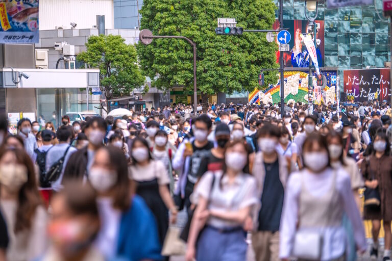 Young people walking in a crowd on the sidewalk towards the camera