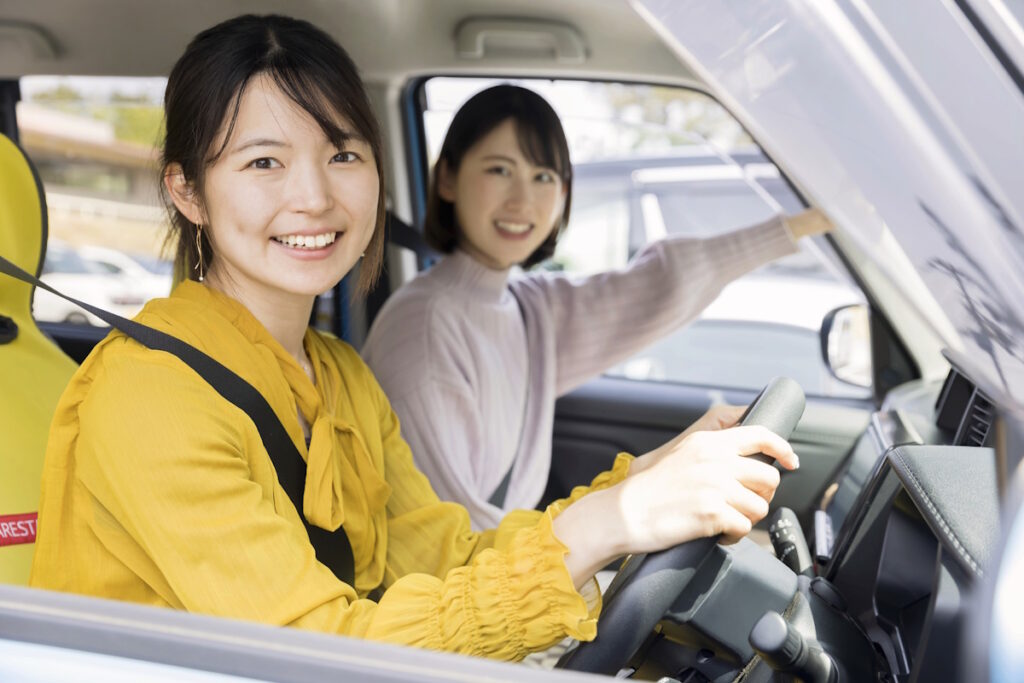 Two women in a car, one dressed in a yellow top driving