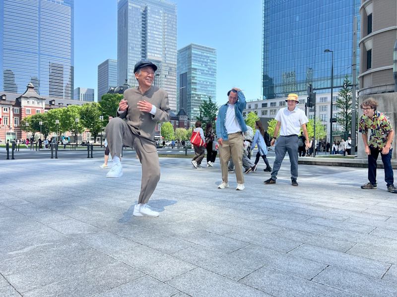 Tohru grooves to the beat (right leg raised, smiling) as three fans from Hawaii look on