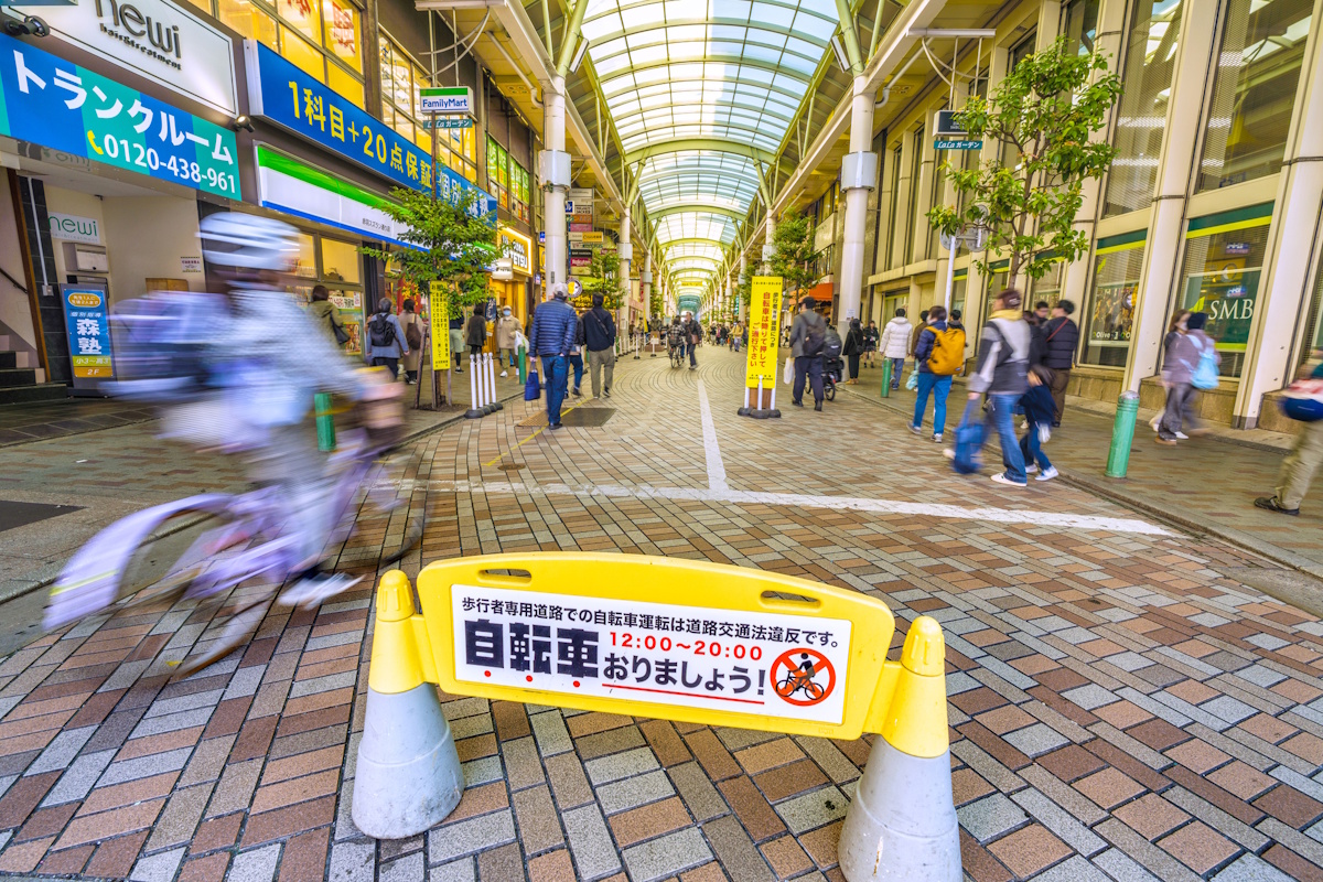 Person running bike into an area with a sign that reads "Please dismount from your bikes"