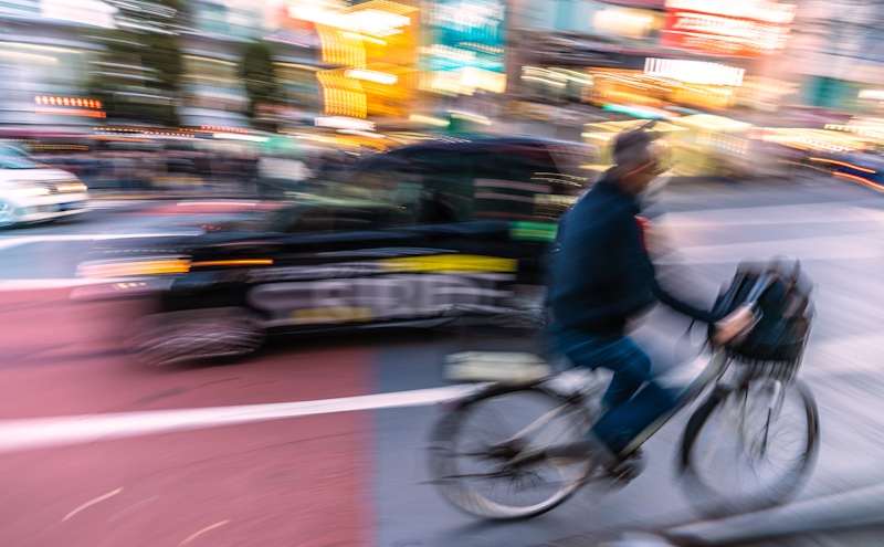 Cyclists riding in the opposite direction, passing a taxi