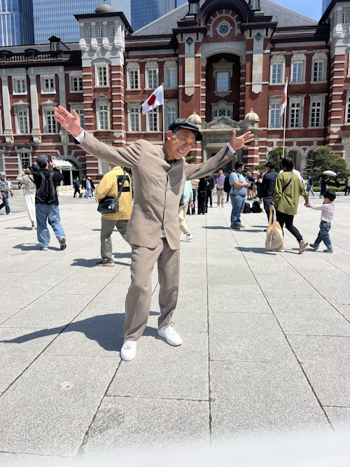 Tohru posing with his hands up from his sides in front of Tokyo Station