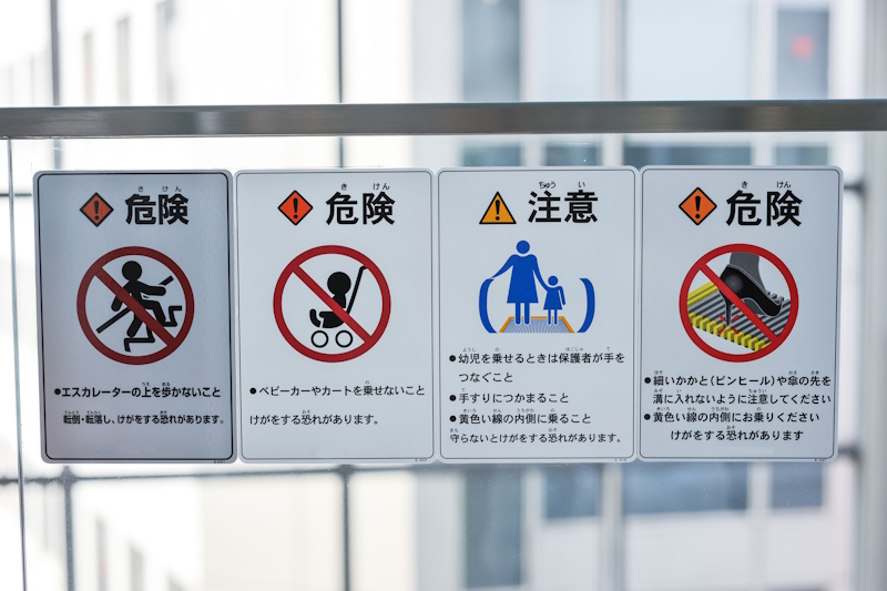 A series of escalator safety signs. The leftmost sign urges people not to walk on escalators as it can lead to falls or injuries.