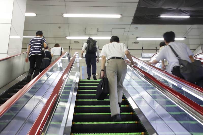 People walking up escalators in a train station