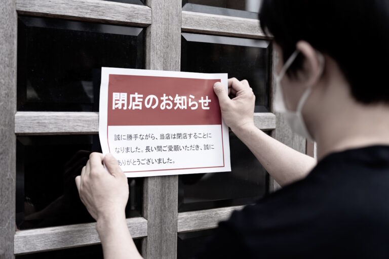 Man putting a "Store Closed" sign on a storefront