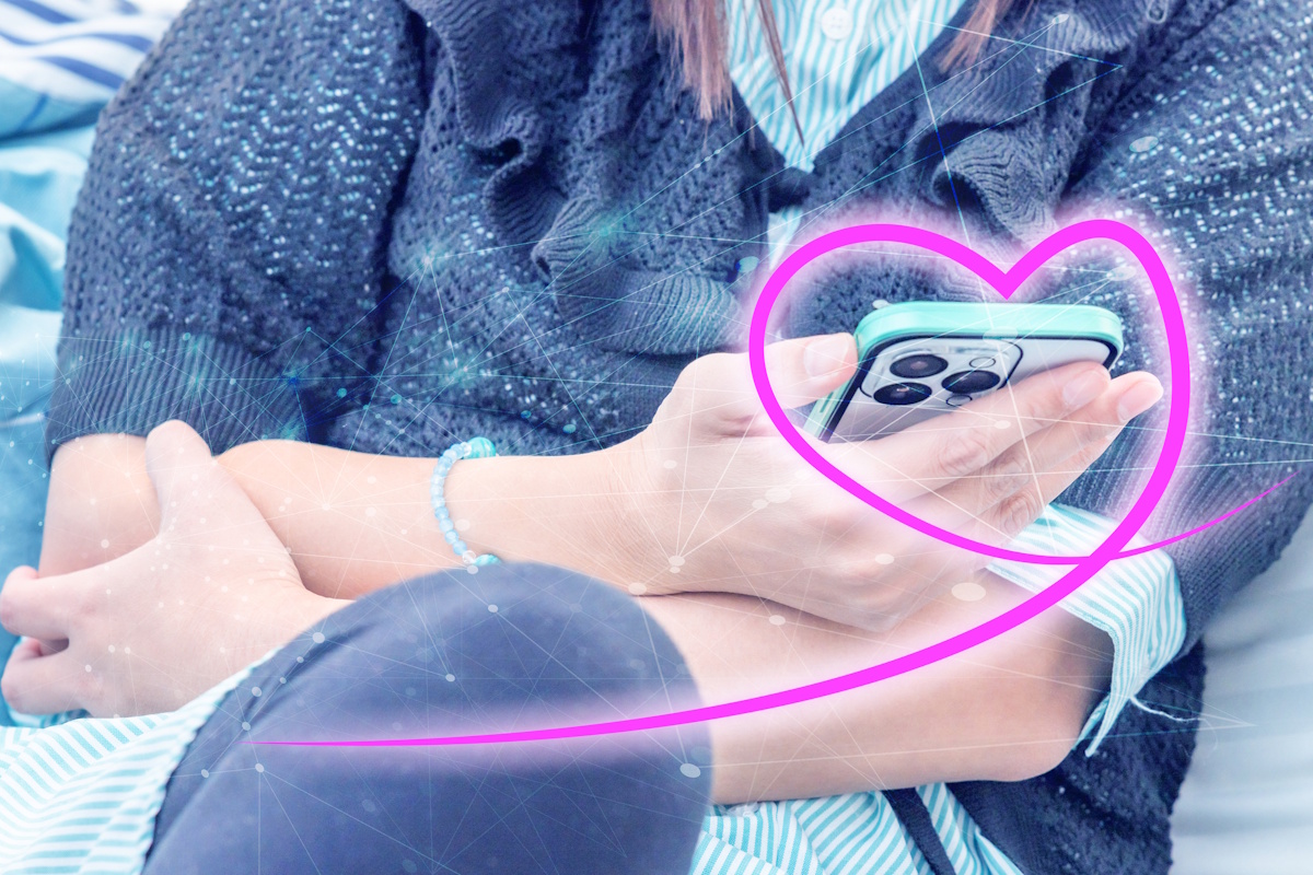 Woman using smartphone with a heart drawn over the hand holding the phone