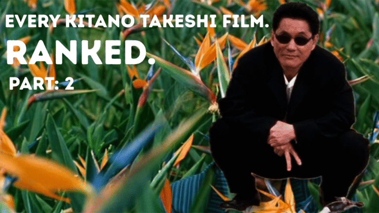 Kitano Takeshi crouches in a suit, with his fingers pointing downwards with two fingers revealed in a baseball single. He's superimposed over a bed of birds of paradise flowers.