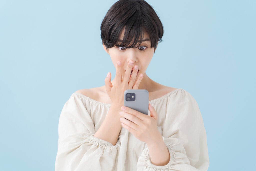 Woman looking at her phone in shock and horror