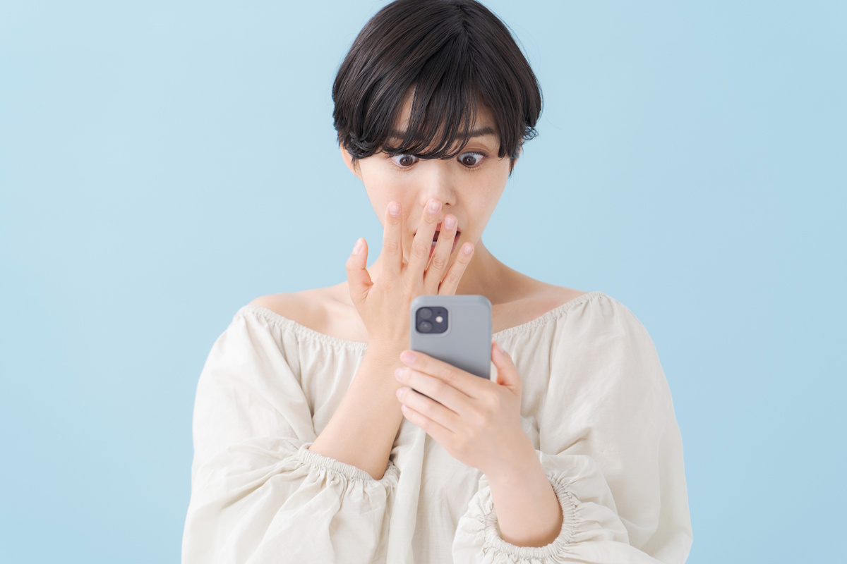 Woman looking at her phone in shock and horror