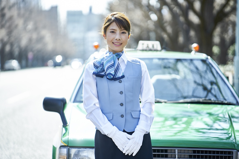 Female taxi driver standing in front of a taxi