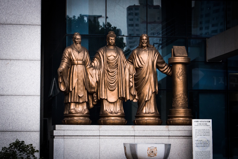 A statue in front of Unification CHurch headquaretrs in Seoul, South Korea, depicting Confucius, the Buddha, Jesus Christ, and the Quran. 
