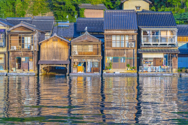 Ine, Kyoto. A line of houses on the waterfront with their reflections shimmering in the water below