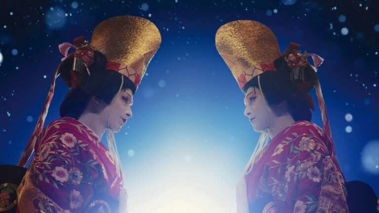 Two onnagata kabuki actors in elaborate matching make-up and costume look towards each other on the poster for the film Kokuho.