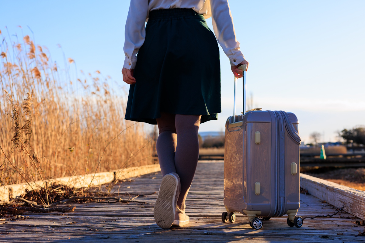 Woman walking down street with roller suitcase