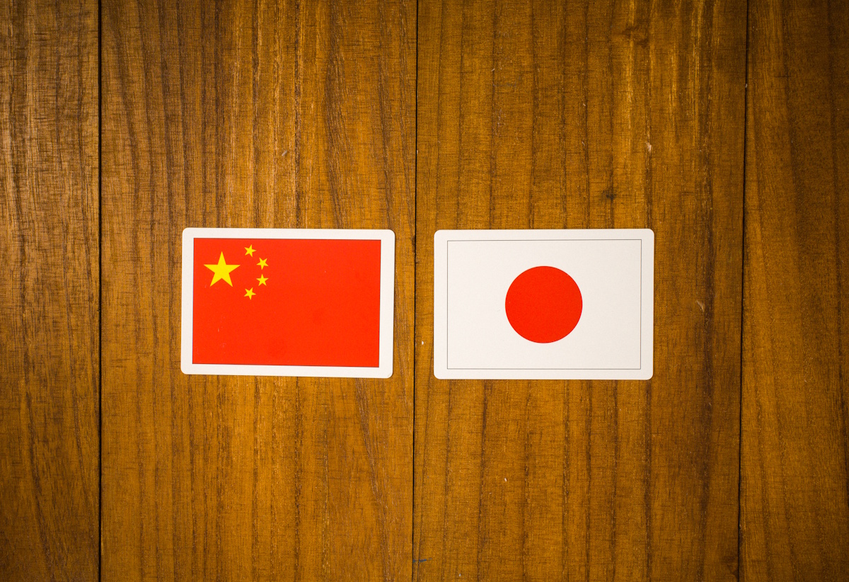 Chinese and Japanese flags against a wooden background