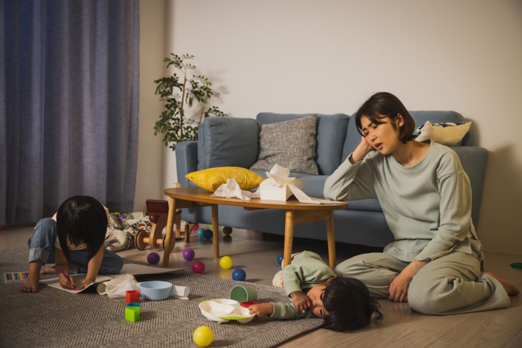 A woman looking exhausted as her two sleepless young children play