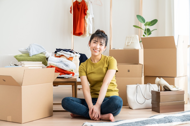 Woman sitting amidst a number of boxes, either packing or unpacking