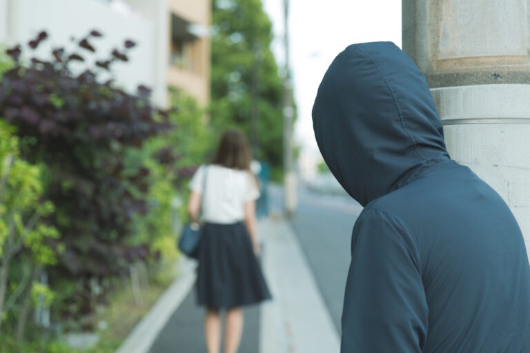 Suspicious man in a hood stalking a woman