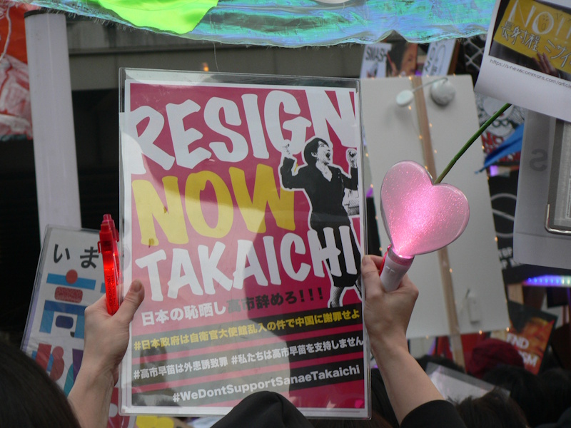 At the March 29th protest rave in Shinjuku, Tokyo, a protester holds up a sign demanding Prime Minister Takaichi Sanae to resign. The sign also demands that the government apologize for the Self Defense Forces service member who recently stormed the Chinese Consulate. (Picture: Emily Boon)