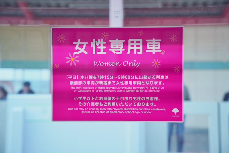 Pink bilingual 'Women Only' sign at a Japanese train station marking a women-only carriage.