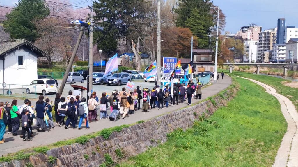 Iwate Rainbow March participants walk along a riverside path in Morioka under clearing skies