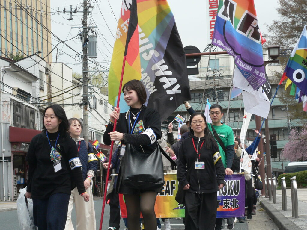 Marchers carry rainbow and Pride flags through a Morioka street, led by Iwate Rainbow March organizers