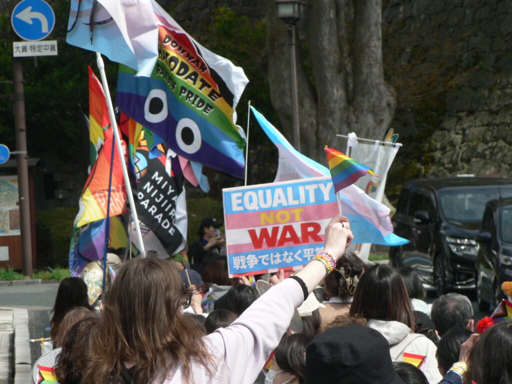 A Pride marcher holds up an anti-war placard.