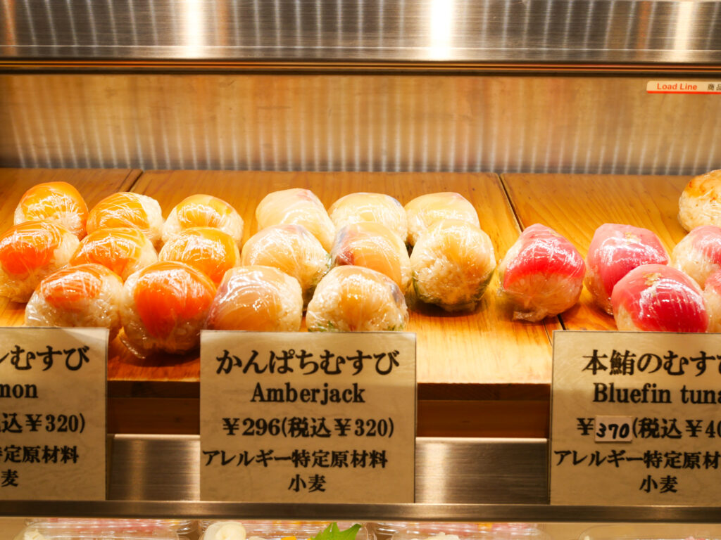 Close-up of wrapped amberjack and bluefin tuna Edomae sushi pieces with handwritten price tags