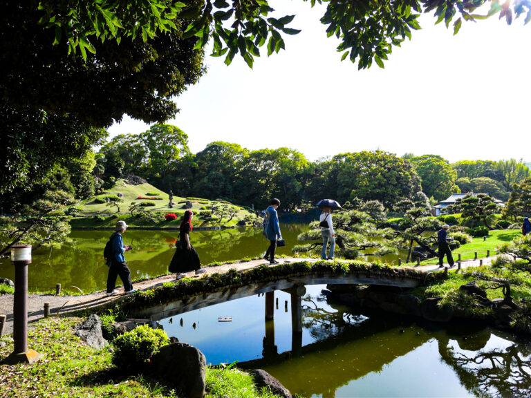 People walking on a bridge over a pond at Kiyosumi Park