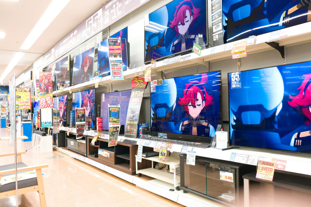 Rows of large flat-screen TVs displaying anime on shelves in a Japanese electronics store