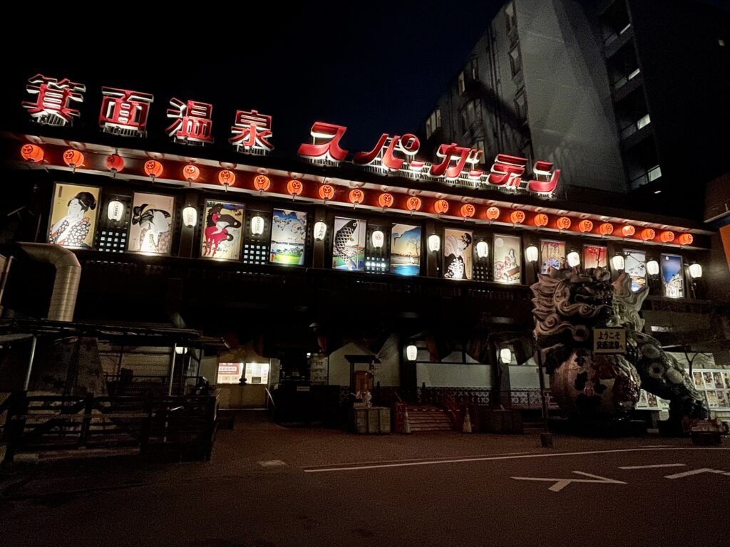 Minoh Spa Garden entrance lit up at night with red lanterns and ukiyo-e style panels