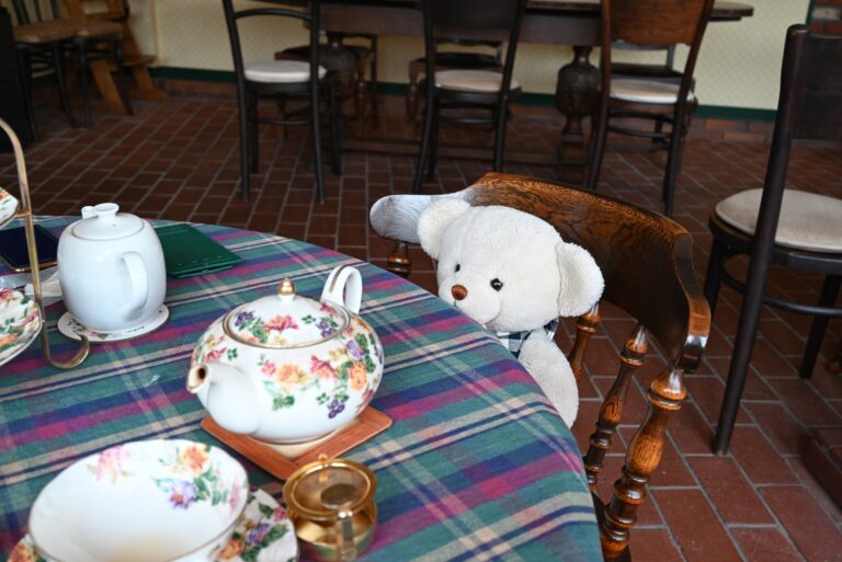 Teddy bear seated at a table with tea set out