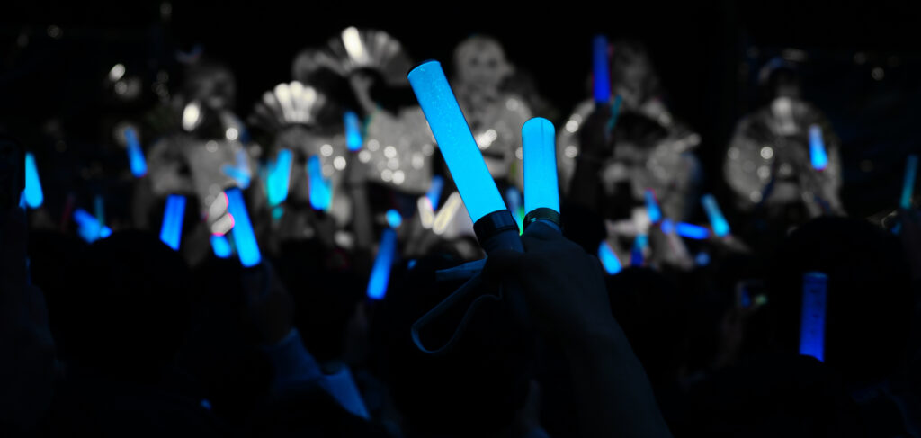 Fans hold up blue glowstick penlights at an idol concert
