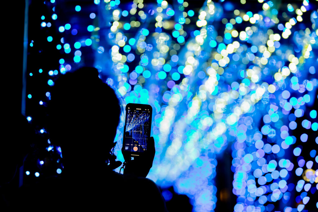 Someone using their smartphone to take a video of a Christmas time light show in Japan