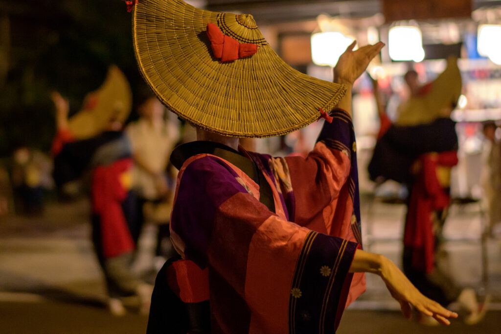Dancer in a colorful patchwork hanuii kimono and straw hat performing at Nishimonai Bon Odori