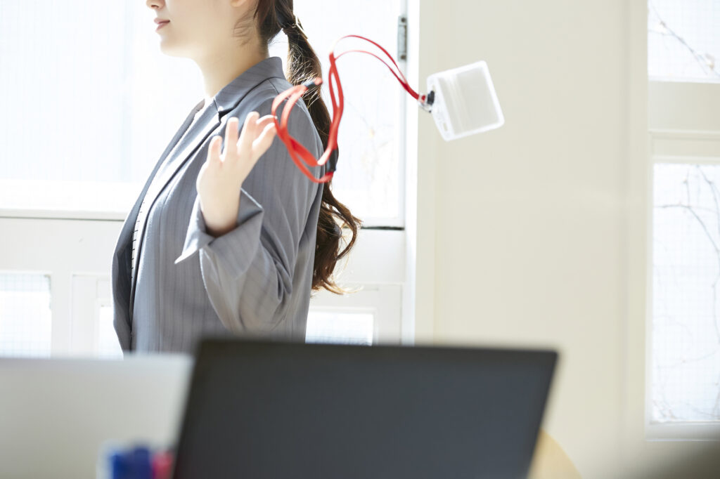 Woman in a gray blazer throwing away her company ID badge as she walks out of the office door in an 
