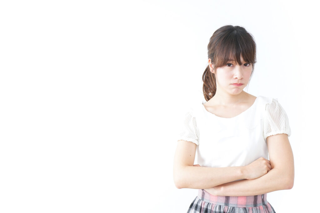 Young Japanese woman standing with arms crossed and a defiant expression