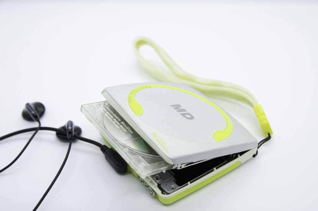 A portable MiniDisc player with earbuds and a disc partially ejected
