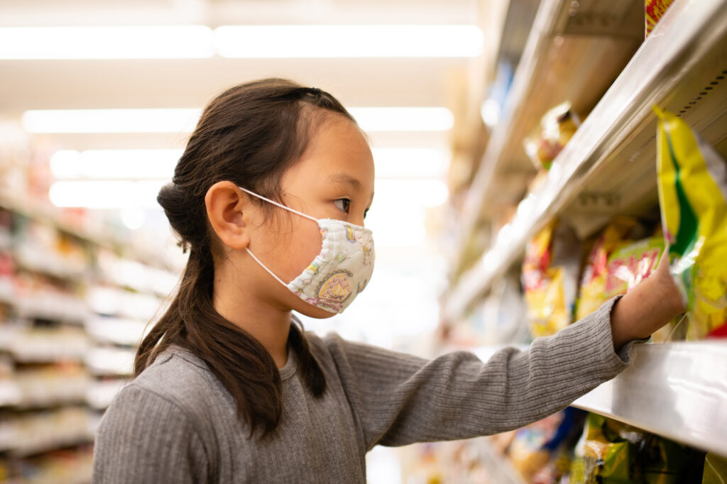 Young girl reaching for snacks on a store shelf in Japan
