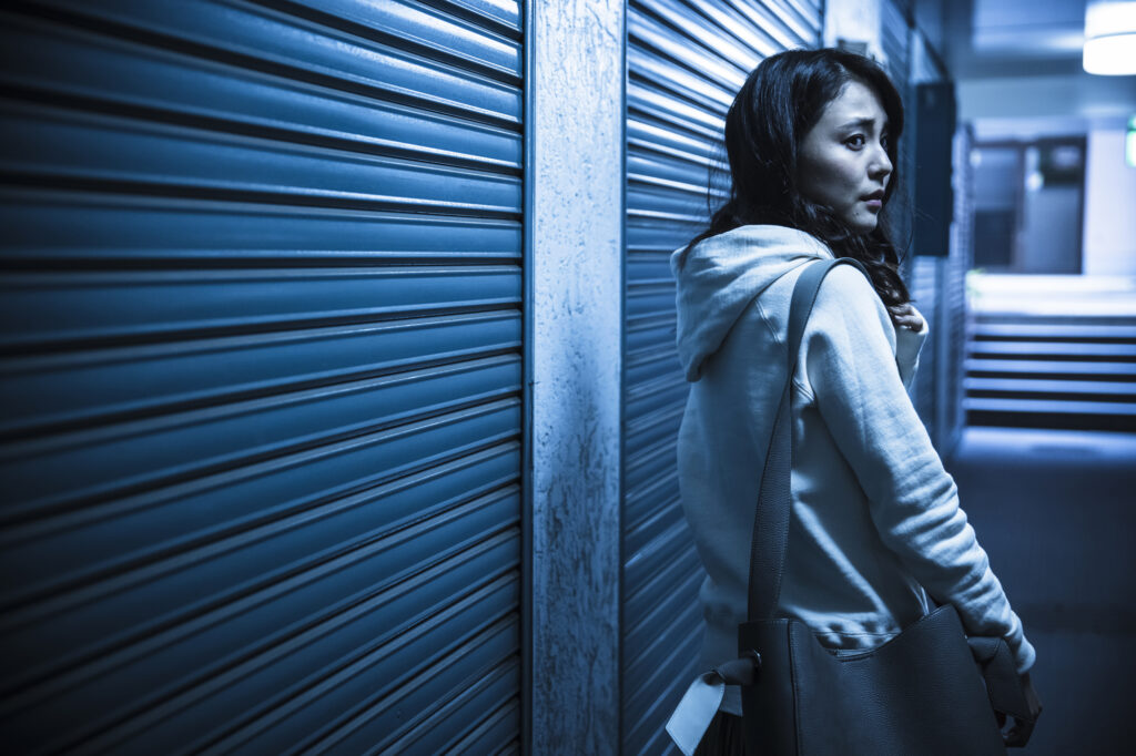 Woman glancing over her shoulder at night near shuttered storefronts