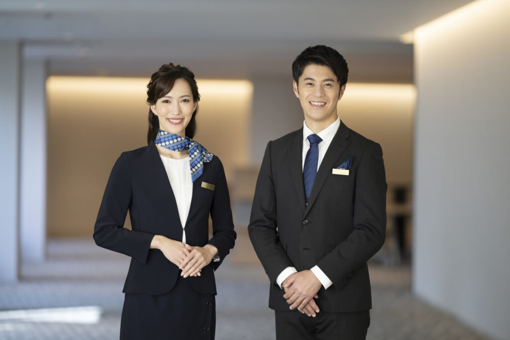 A man and a woman at a fancy hotel in business suits smiling at the camera