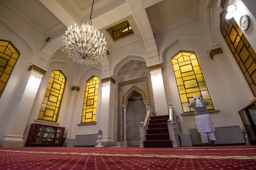 A cleric chants the adhan inside Kobe Muslim Mosque, Japan's first mosque, with its stained glass windows and chandelier
