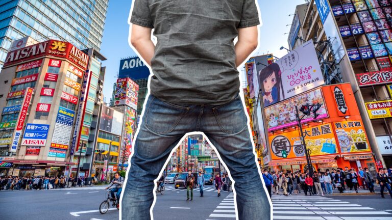 A man stands with legs apart, seen from below, against a busy neon-lit Tokyo street of shops and billboards.