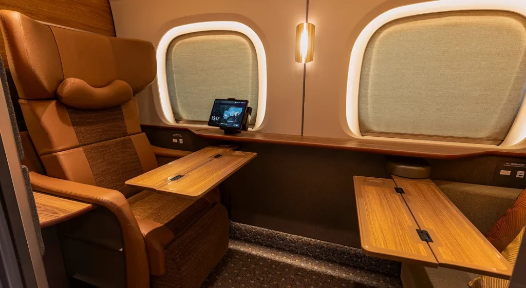 Supreme Class cabin interior with fold-out wooden tables, a seatback control tablet, and two large windows