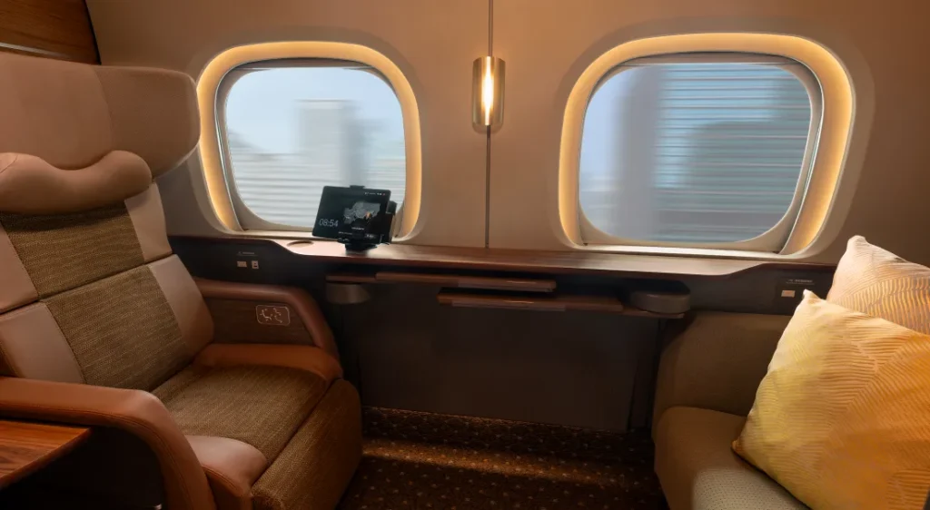The two-person Supreme Class cabin, with a reclining seat, a cushioned sofa, a table, and two windows