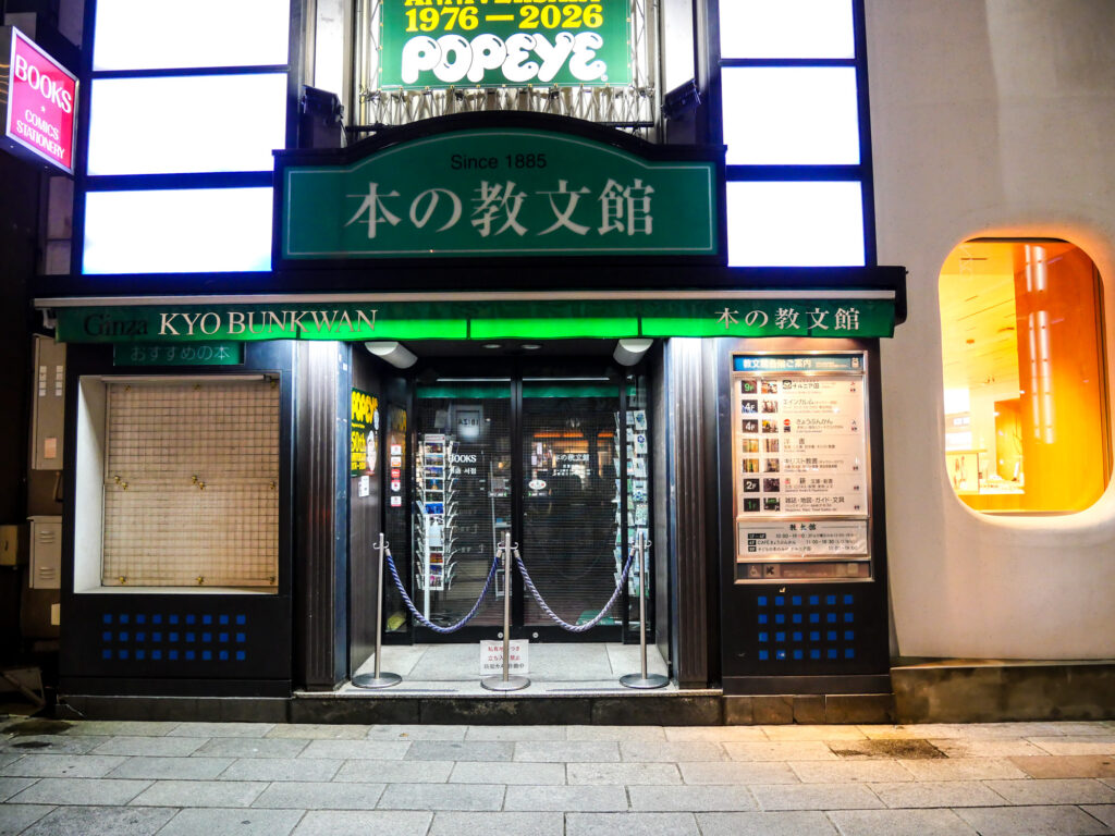 Night view of the Kyōbunkan bookstore storefront in Ginza, green sign reading 本の教文館