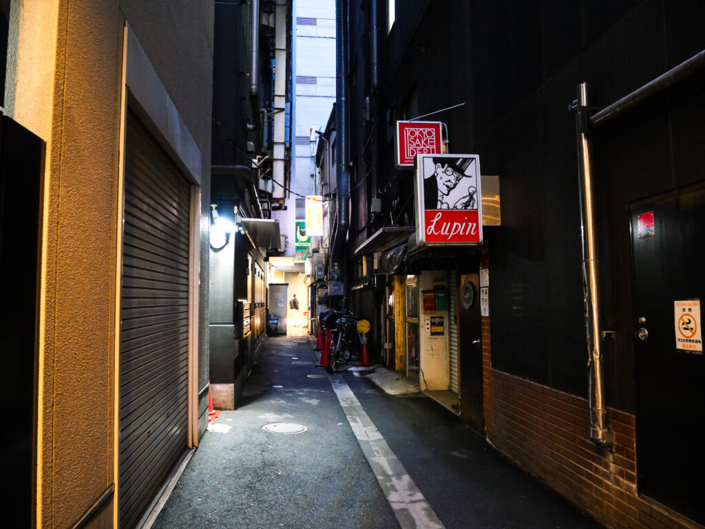 Narrow Ginza alley at dusk with Bar Lupin's projecting sign and its top-hatted gentleman-thief logo