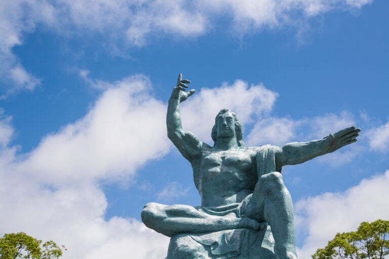 The Nagasaki Peace Statue, a seated bronze male figure with one arm raised skyward and the other extended outward