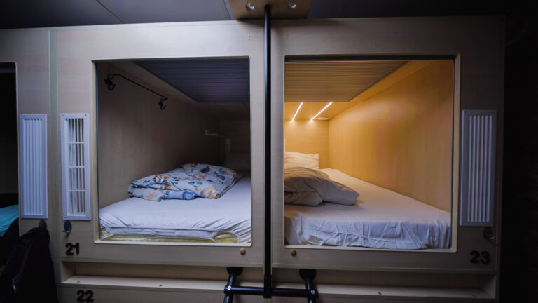 Two open cabin-style hotel pods numbered 21 and 23, each with a single bed and wood-paneled interior