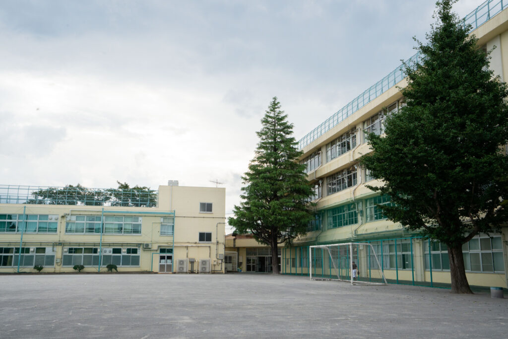 Exterior of a Japanese middle school building and empty schoolyard with a soccer goal